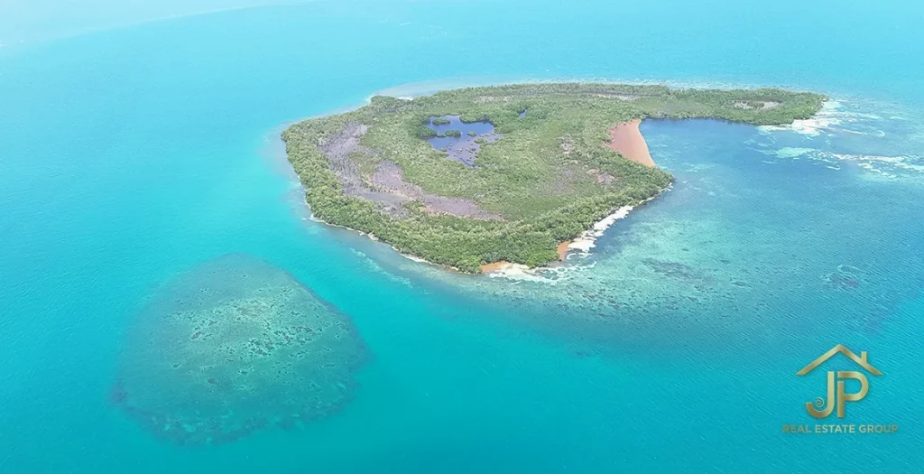 Wide aerial view of the island, sandy shoreline, and surrounding reef areas